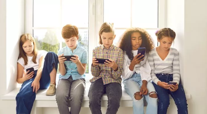 Група малки деца гледат своите смартфони