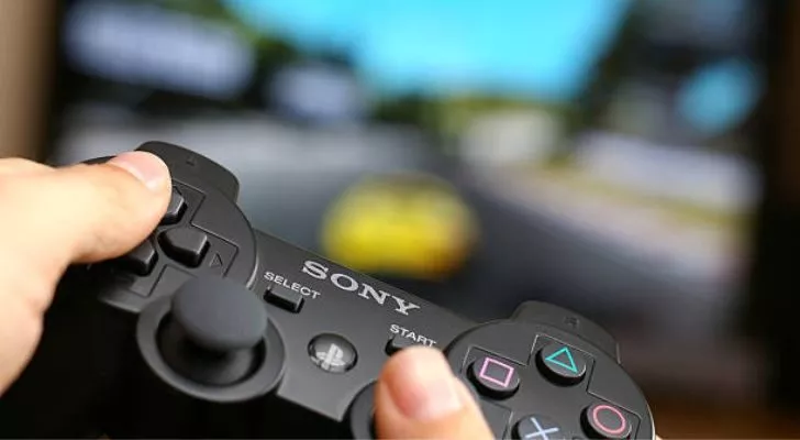 Човек, който играе игра, държи PS3 контролер. 