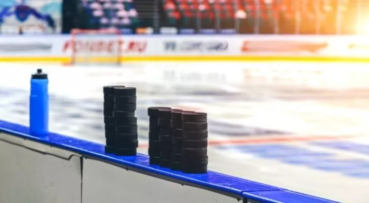 Купчина шайби за хокей отстрани на ледената пързалка.