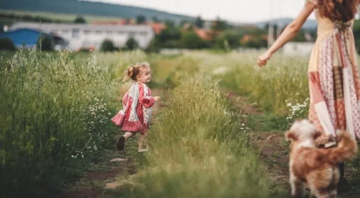 Малко дете, тичащо през тревно поле с майка си