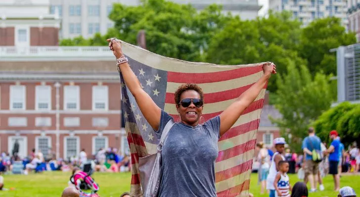 Човек, който държи флага на САЩ в парк.