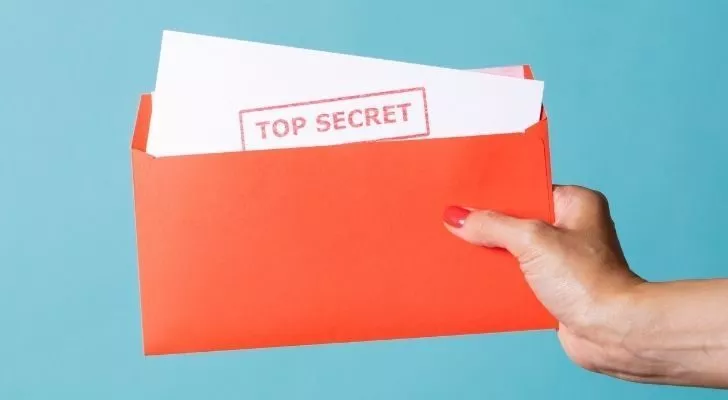 Лице, което държи лист хартия с надпис "строго секретно".