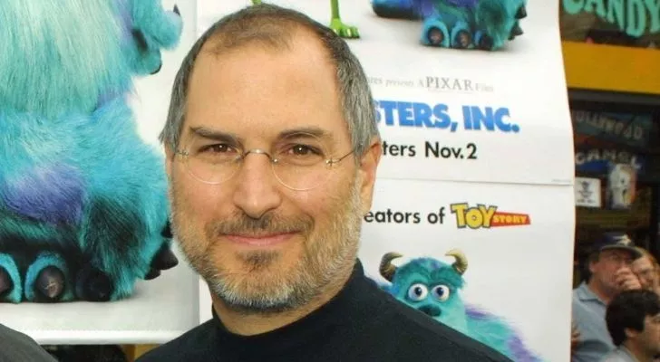 Стив Джобс с плакат на Pixar зад него