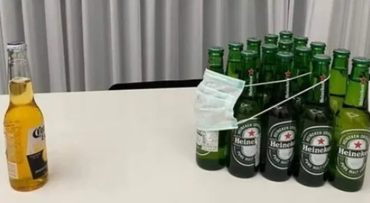 Една бутилка бира Corona срещу тълпа от бутилки бира Heineken, които са социално дистанцирани от Corona и носят маска за лице