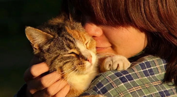 A cat person hugging a cat on her shoulder