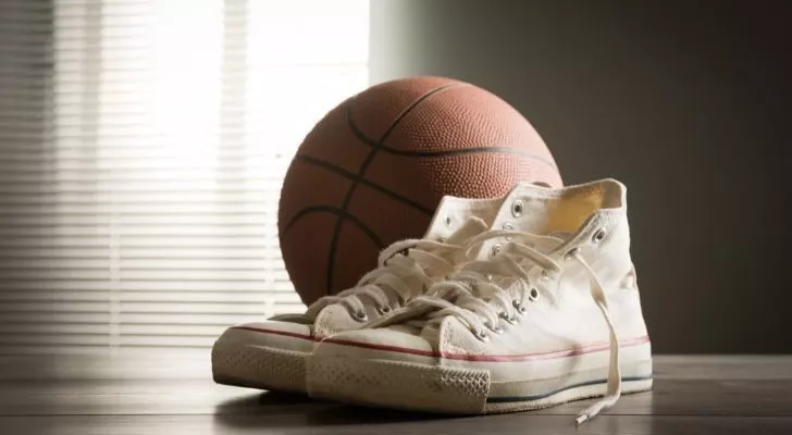 Бели обувки Converse с ниско изрязване, разположени до баскетболна топка