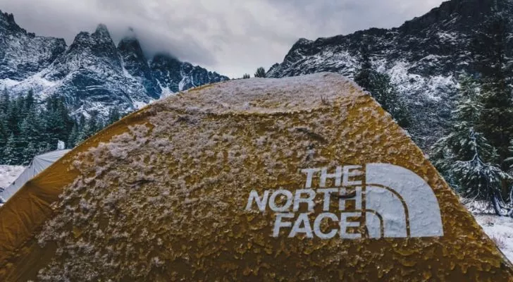 Палатка на North Face, покрита със сняг, със снежни планини на заден план