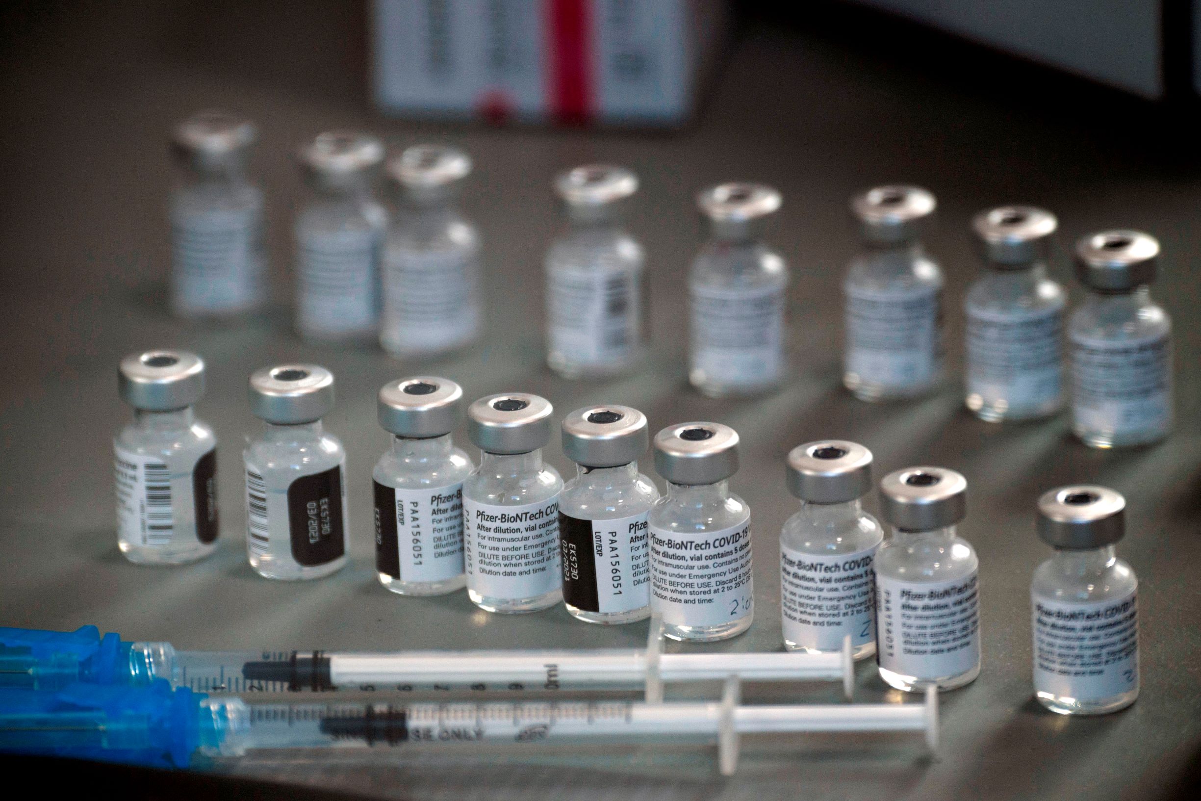 Флакони с ваксината Pfizer-BioNTech Covid-19, подредени на маса до няколко спринцовки