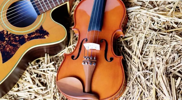 Китара и цигулка една до друга върху слама