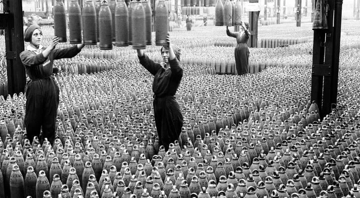 Three women work in a huge warehouse with shells stretching as far as the eye can see