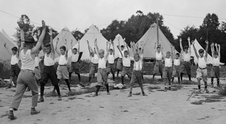 A group of young American boys do physical drills with an instructor