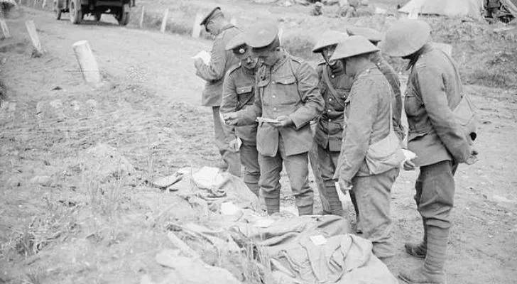 A group of men sort through a large pile of bags containing letter to and from soldiers