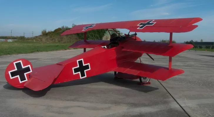 A red triplane with German crosses sits on a run way