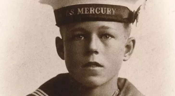 A young boy wearing a naval uniform poses for a photo