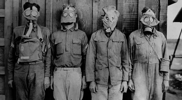 Four men from WWI wear different gas masks