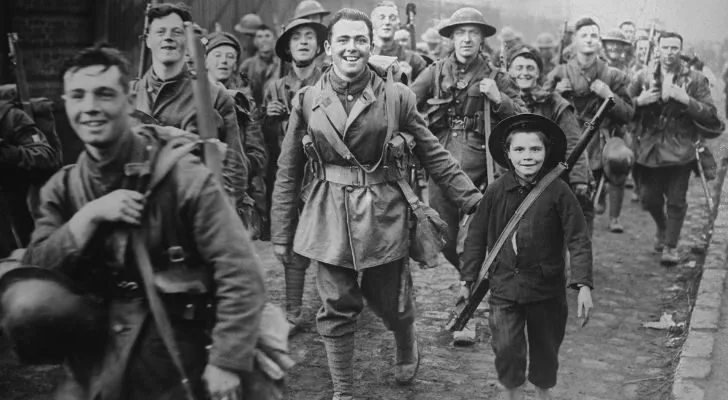 A group of British soldiers and local civilians smile while walking