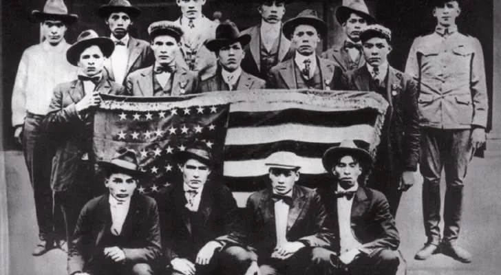 A group of Native Americans pose with an American flag