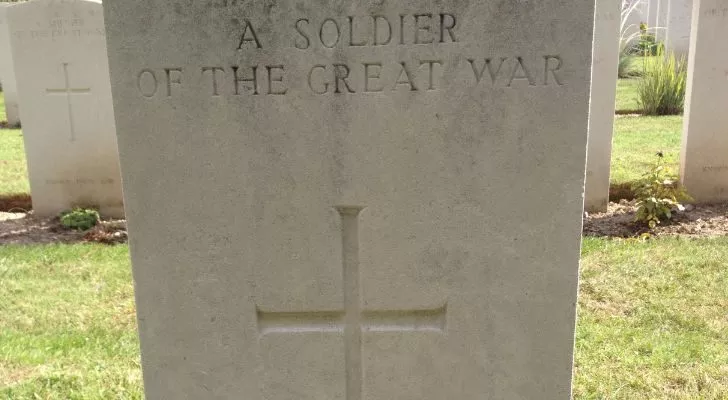 A white grave stone with a cross engraved and the words "A soldier of the Great War"