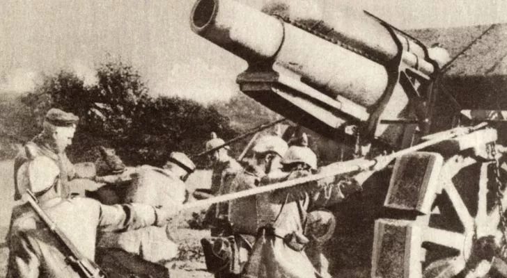 German soldiers strain as they pull a huge piece of German artillery
