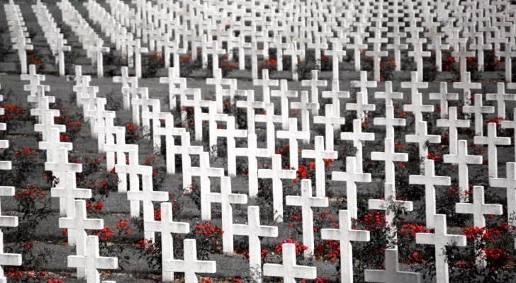 A huge field of white cross grave stones and red flowers