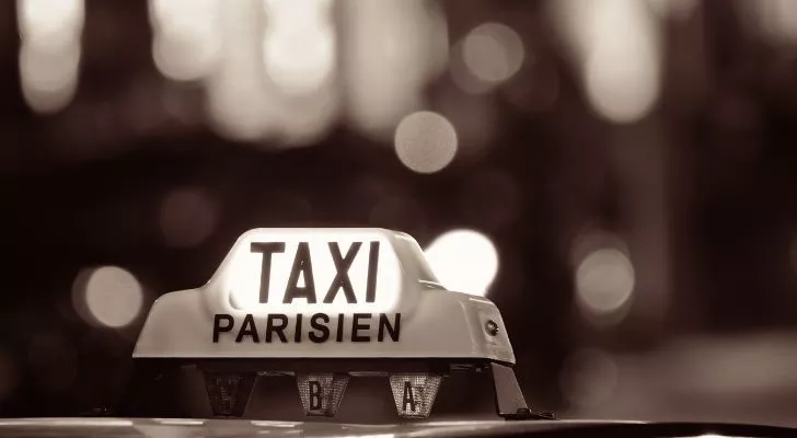 A taxi sign with the word Parisien on top of a car
