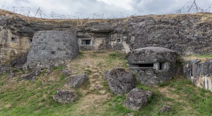 A fort that is built into a hill with small bunkers and barbed wire