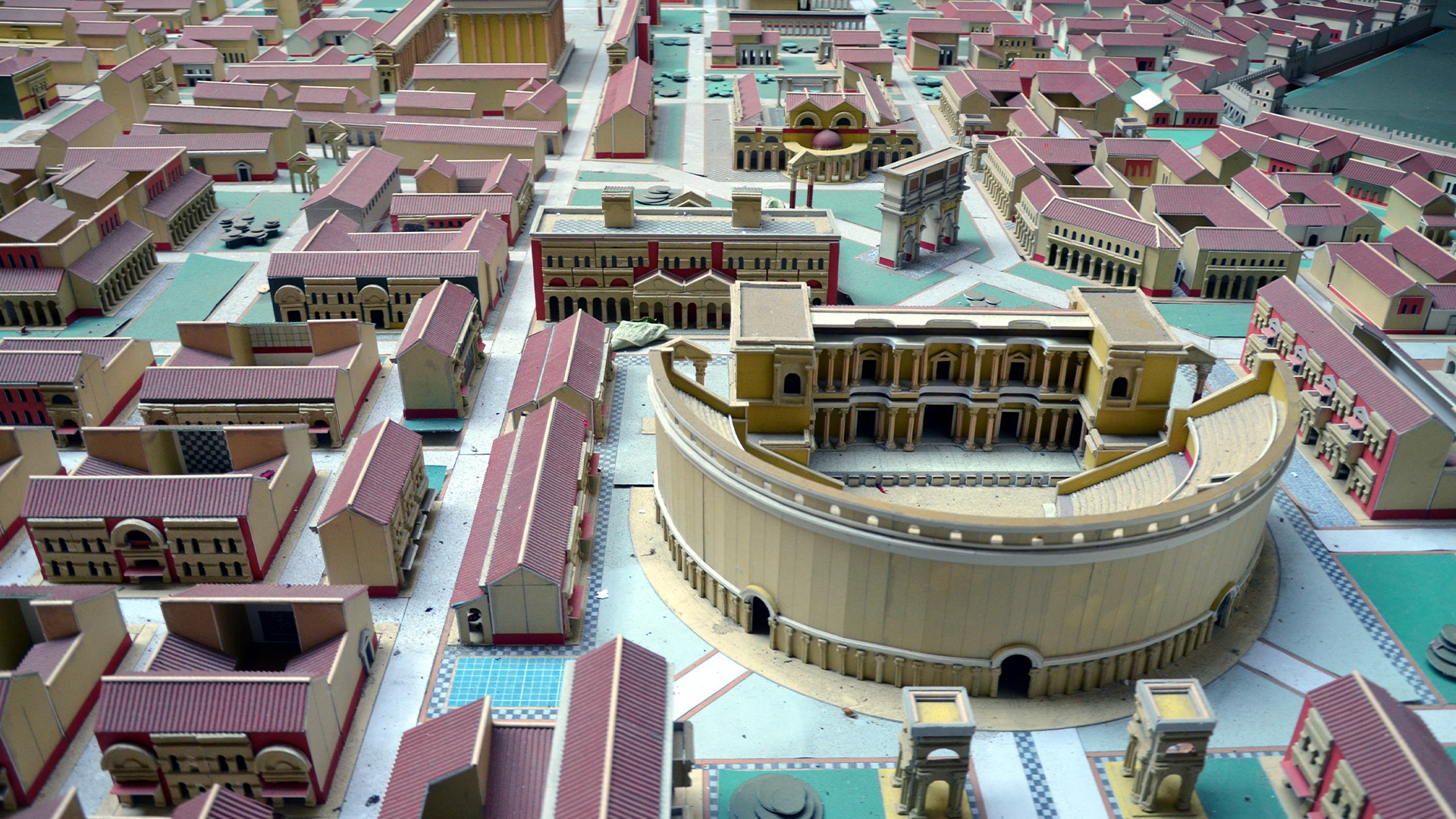 Виждаме виртуален модел на римски град със сгради с червени покриви и амфитеатър.