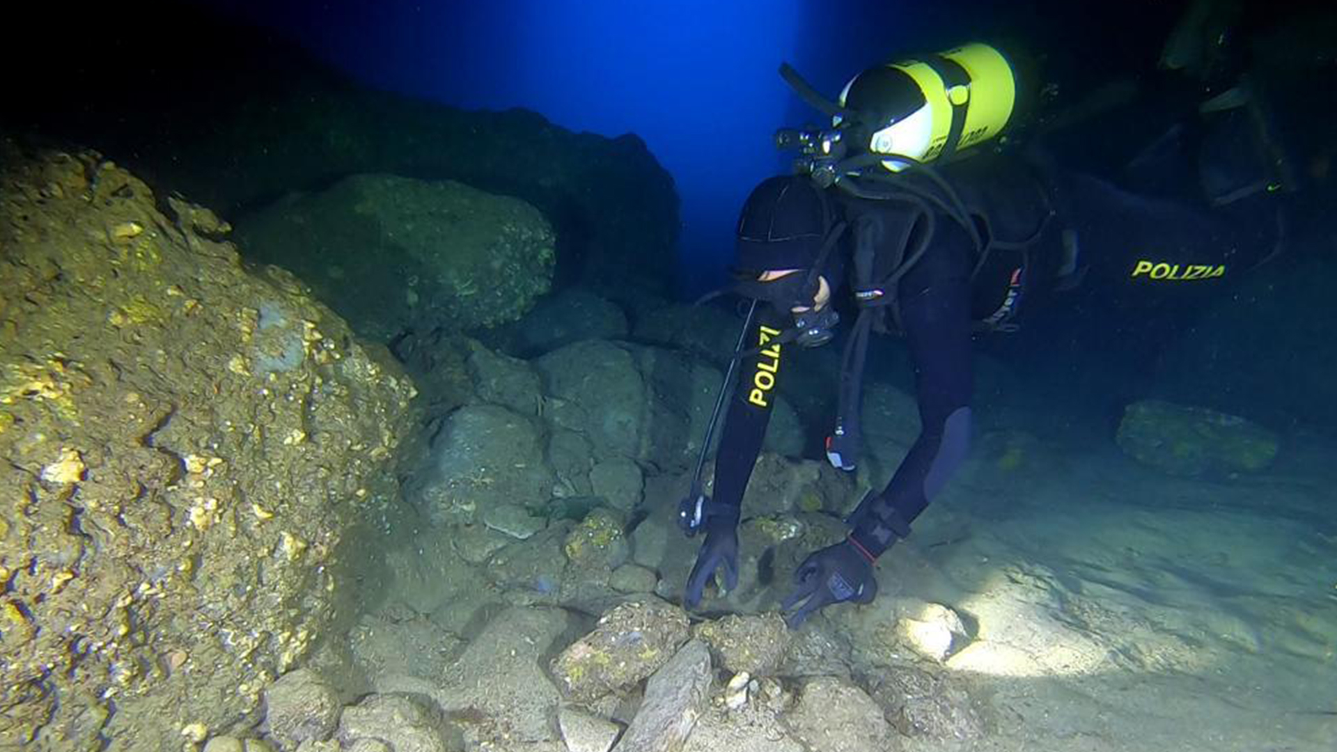 Гмуркач с жълт резервоар гледа подобни на скали бучки на морското дъно.