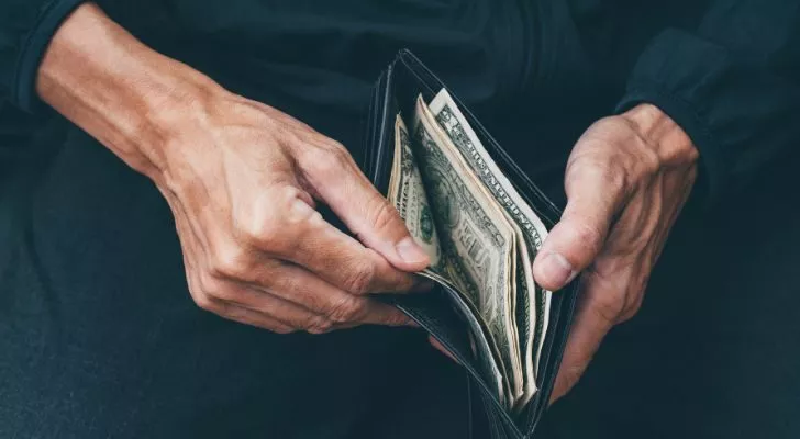 Мъж отваря портфейл и намира в него само малка сума пари