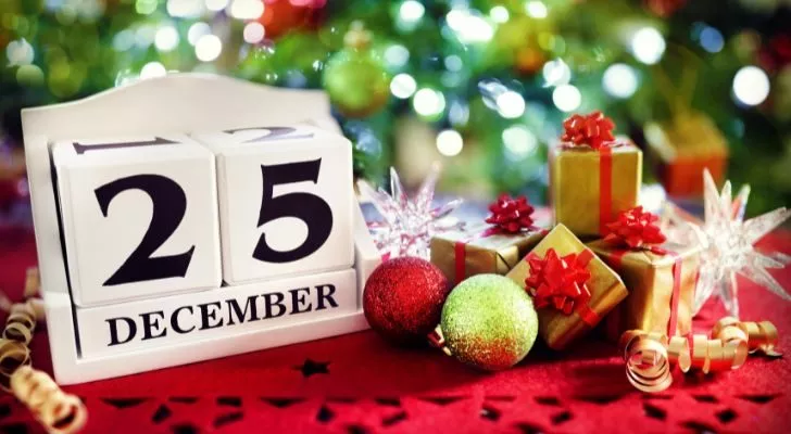 Някои малки коледни подаръци стоят до календар, показващ 25 декември