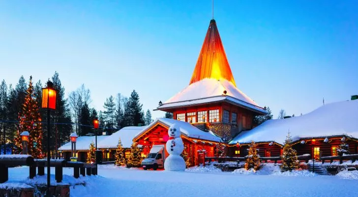 Покрита със сняг сграда със снежен човек отпред