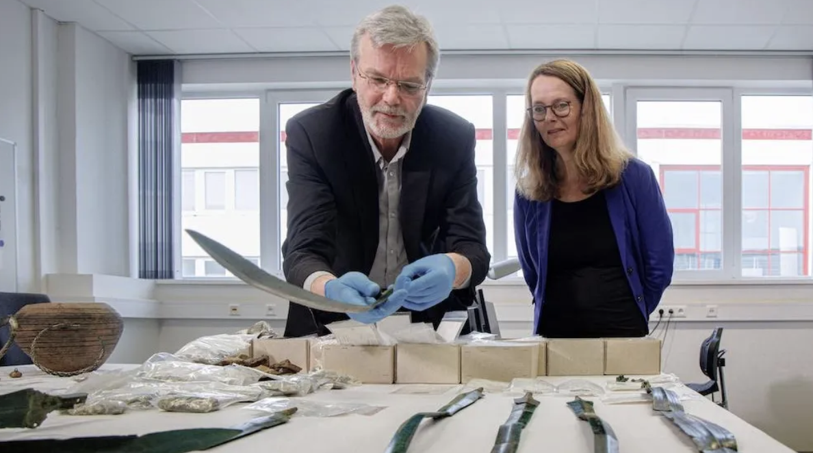 Археологът Детлеф Янцен (вляво) и Бетина Мартин, министър на науката и културата, разглеждат най-новите археологически находки от Германия, включително мечове от бронзовата епоха и хиляди сребърни монети.