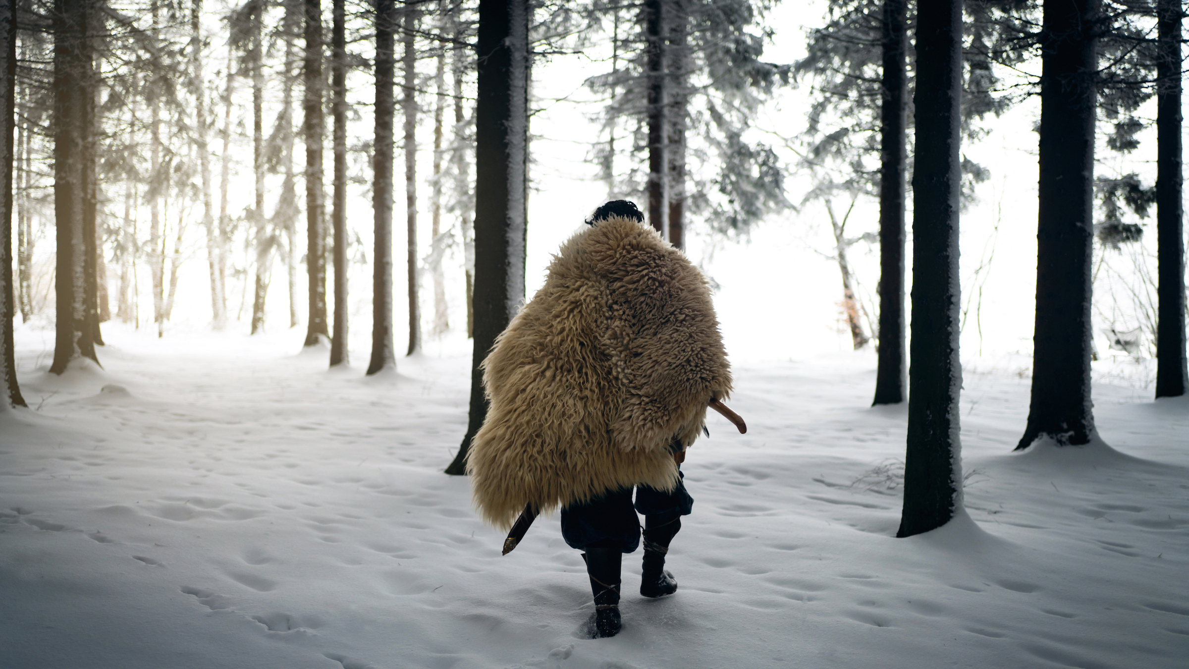 Съвременно изображение на воин от ледниковата епоха, облечен в животинска козина и разхождащ се в снежна гора.