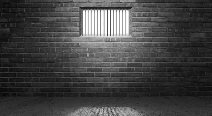 Слънчевата светлина прониква в затворническа килия през прозорец с решетки