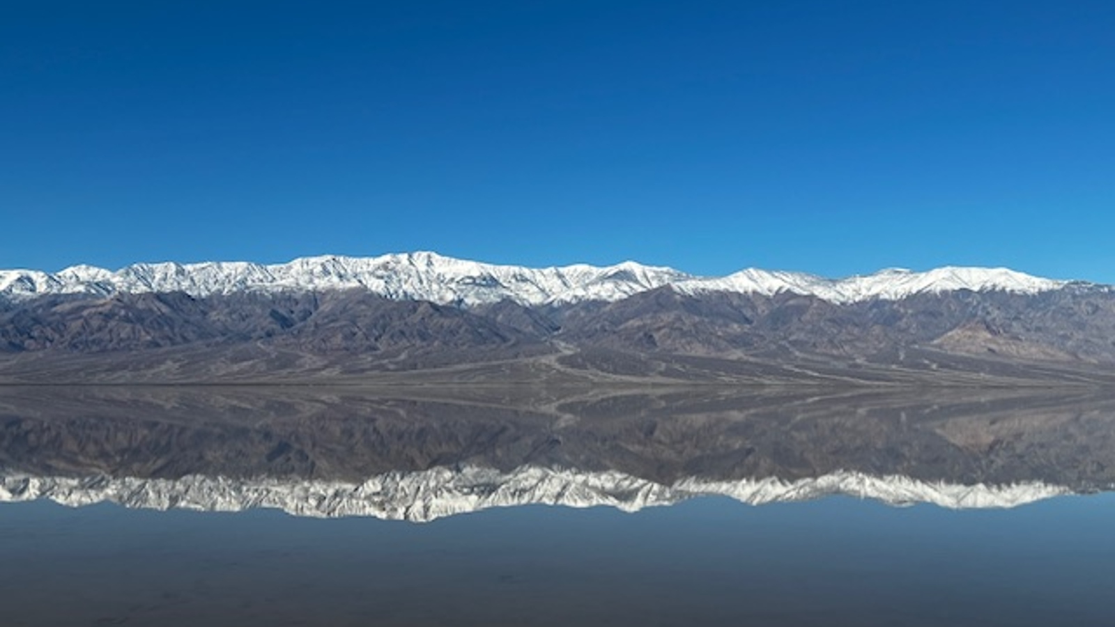 заснежени планини, отразени в съвършено неподвижно езеро