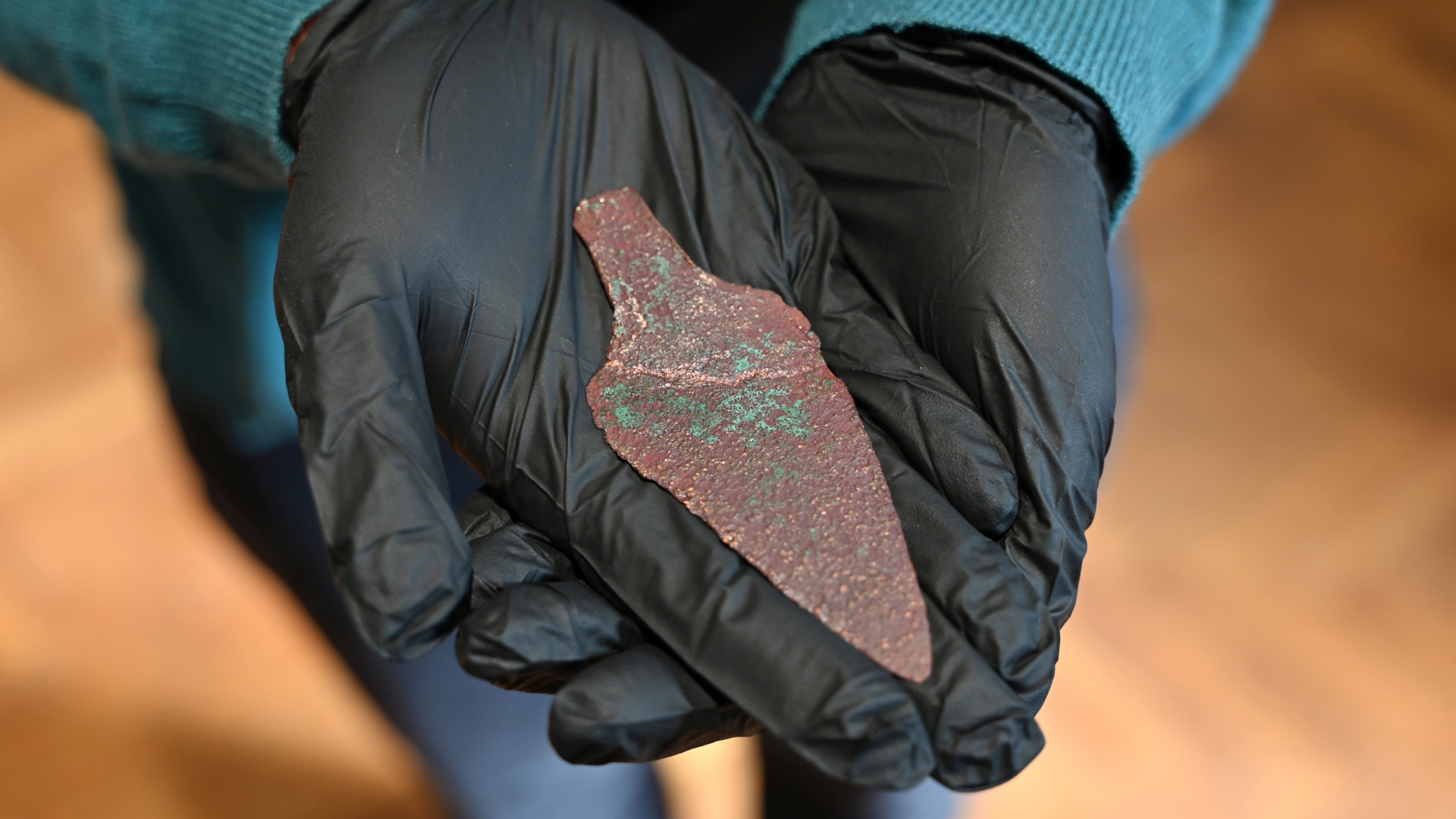 Изследовател в черни ръкавици демонстрира медна кама на повече от 4000 години.