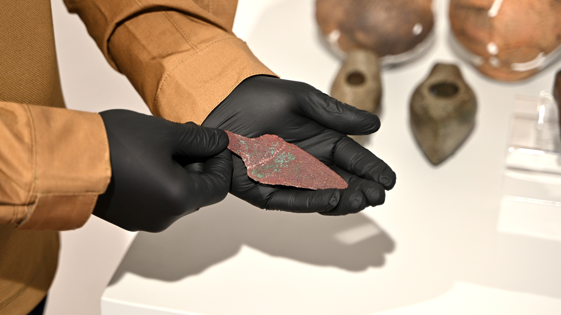 Изследовател в черни ръкавици демонстрира медна кама на повече от 4000 години.