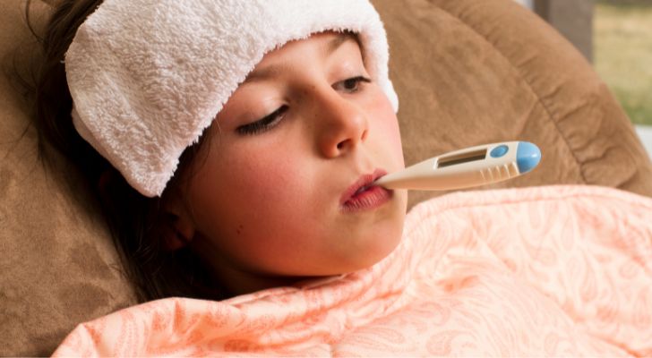 Дете в леглото с термометър в устата
