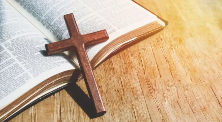 Малък дървен кръст се опира на отворена Библия