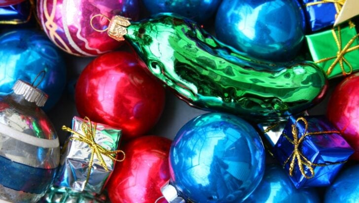 Орнамент от зелено стъкло, заобиколен от цветни коледни топчета и малки опаковани подаръци