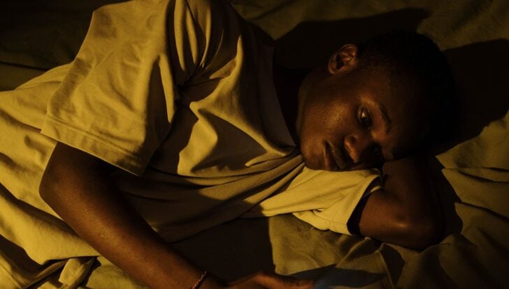 Човек, който лежи в леглото с разстроено изражение